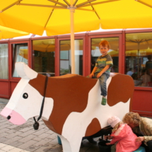 Kind reitet auf der Spielkuh im Innenhof.